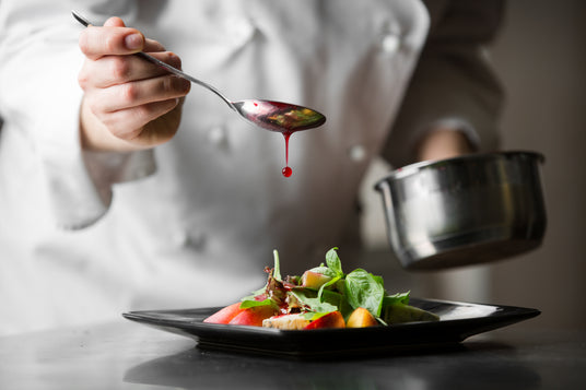 Chef garnishing a dish with a spoonful of sauce