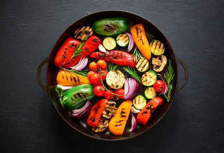 Assorted grilled vegetables in a pan on a dark background